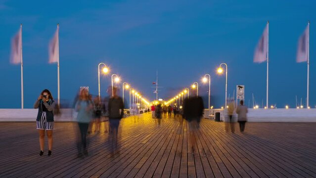 Sopot, Poland. An evening time-lapse of a long wooden pier in Sopot, Poland, with a view of blurred people and a blue sky