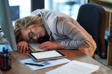 Putting in a bit too much time at the office. Cropped shot of a businesswoman sleeping at her desk while working late in the office.
