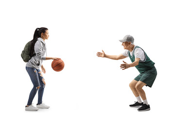 Fototapeta na wymiar Full length profile shot of a female student and an elderly man playing basketball