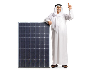 Full length portrait of a mature man in arab etninc clothes leaning on a solar panel and pointing up