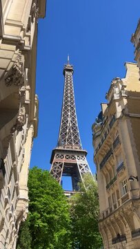 The Eiffel tower with warm rays of light in clouds during sunset timelapse hyperlapse. It is one of the most recognizable landmarks in the world. Blue cloudy sky at sunny evening. 