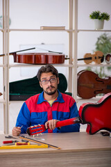 Young man repairing musical instruments at workshop