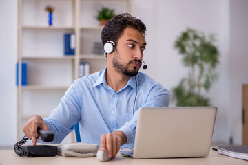 Young male call center operator working at his desk