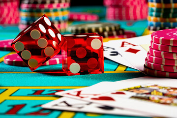 Red dice, game cards and colored chips for playing poker on gaming table in casino. Concept of gambling, betting, leisure. Background of poker game, entertainment, risk, gaming lifestyle. Close up.