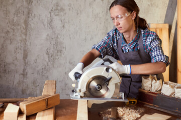 Skilled female carpenter using a circular saw. Woman worker in the carpenter workroom renovation....