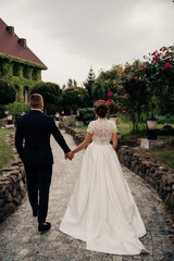 the bride and groom in a lush white dress are standing in the rain against the backdrop of a beautiful building overgrown with ivy