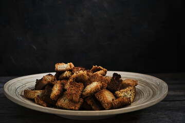 Wooden plate with fried breadcrumbs dark background. Rustic setting and food.