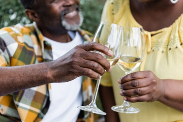 cropped view of senior african american couple clinking glasses of wine.