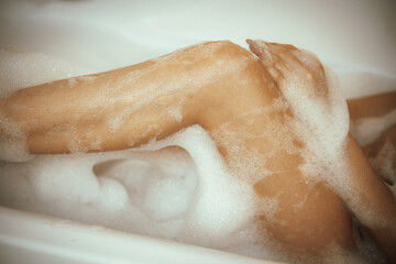 Fototapeta premium Women's feet in bath foam. View from above. Enjoy and relax in a spa hotel