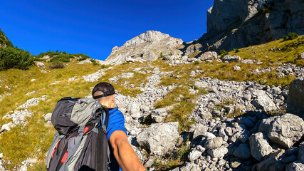Man with backpack filming himself while hiking to the summit of Hinterer Polster in the scenic...