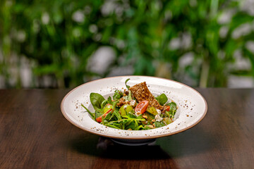 Green salad on a wooden table with floral backround.