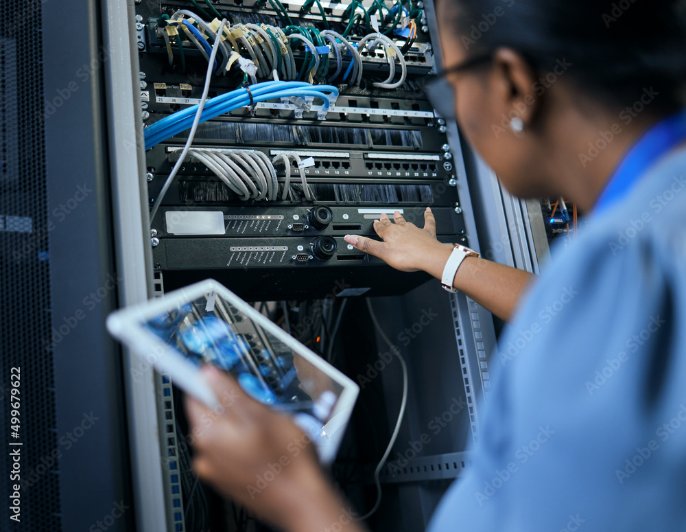 Poster Sorting out network issues. Rearview shot of an unrecognizable female programmer working on a tablet in a server room.