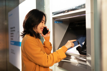 Happy smiling young woman withdrawing money from credit card. Young woman typing pin code on keypad...