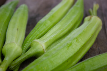 FRESH OKRA, Abelmoschus esculentus RECENTLY HARVESTED FROM AN ORGANIC GARDEN, ON A RUSTIC WOODEN TABLE WITH NATURAL LIGHTING
