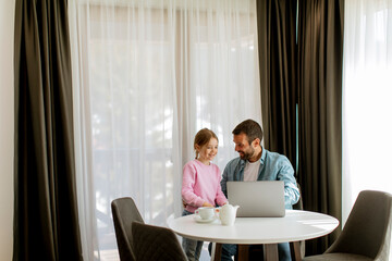 Father and daughter using laptop computer together