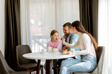 Happy young famila eat cakes and drink tea together