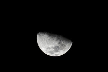 First Quarter Moon Phase on a clear sky night, half lit waxing gibbous