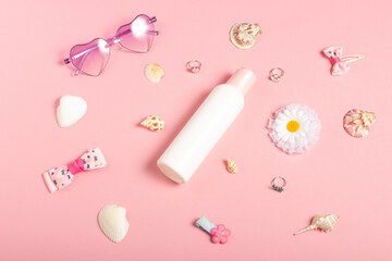 Baby cream, hair accessories and jewelry on a pink background. Little girls accessories, flat lay