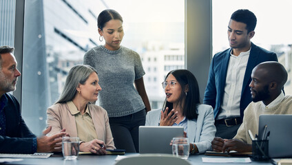 The dream team together at last. Shot of a group of businesspeople using a digital tablet during a meeting.