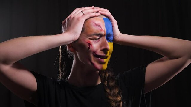 girl with the flag of Ukraine on her face and with wounds holding her head and screaming in hysterics