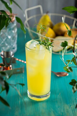 Pear Collins Cocktail. Highball glass filled with pear puree cocktail or mocktails surrounded by ingredients and bar tools on turquoise table