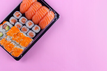 Salmon sushi set delivery box with maki and california on pink background