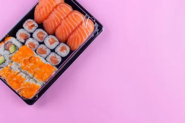 Fotobehang Salmon sushi set delivery box with maki and california on pink background © Viktorua