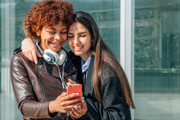 girls smiling in the street looking at the mobile phone