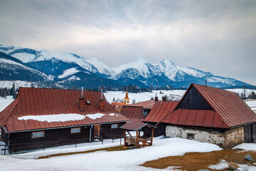 Folk architecture of the distinctive village of Zdiar with a panorama of mountains in the background at winter. High Tatras National Park, Slovakia, Europe. - obrazy, fototapety, plakaty