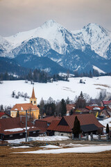 Fototapeta premium Folk architecture of the distinctive village of Zdiar with a panorama of mountains in the background at winter. High Tatras National Park, Slovakia, Europe.