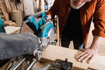 partial view of carpenter cutting board with miter saw in woodwork studio.