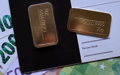 Gold bars on the background of euro banknotes of various denominations. Selective focus.