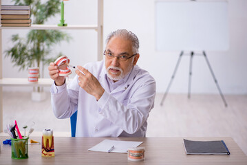 Old male dentist working in the clinic