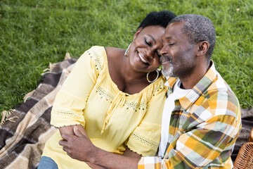 joyful and senior african american couple with closed eyes hugging during picnic.