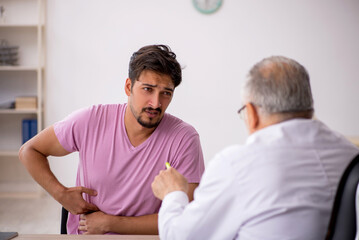 Fototapeta premium Young male patient visiting old male doctor