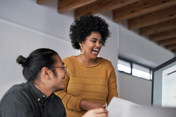 Laughing with coworkers is the best feeling. Cropped shot of two young businesspeople working on a computer together in the office during the day.