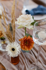 Wedding Decor. Festive table decorated with flowers on the center, candles, silverware and plates with silk napkins on dusty blue tablecloth