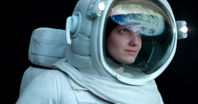 Portrait of Caucasian female astronaut during spacewalk. Earth reflecting in helmet visor. Space exploration concept. Shot with 2x anamorphic lens