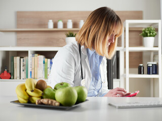 distracted female nutritionist chatting with smartphone in office studio