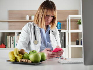 distracted female nutritionist chatting with smartphone in office studio