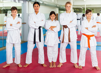Portrait of teenager children with their female instructor posing at gym after group training