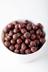Juniper berries on white background. Juniper seeds in a white bowl isolated.