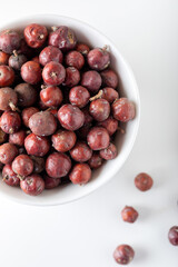 Juniper berries on white background. Juniper seeds in a white bowl isolated.