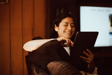 Mujer contenta trabajando en su tableta. Concepto de hogar y trabajo (tecnología).