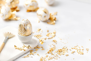 Obraz na płótnie Canvas Easter white egg decorated with golden potal on white background. Eeaster diy concept.