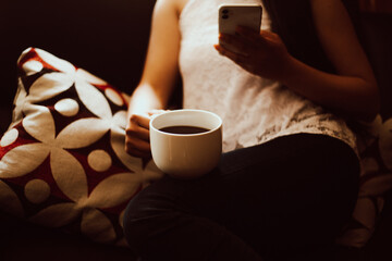 Mano de mujer sosteniendo una taza de café y el teléfono. Concepto de estilo de vida y tecnología