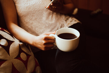 Mano de mujer sosteniendo una taza de café y el teléfono. Concepto de estilo de vida y tecnología