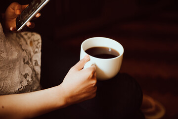 Mano de mujer sosteniendo una taza de café y el teléfono. Concepto de estilo de vida y tecnología