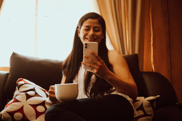 Mujer sonríe mientras lee algo en su teléfono móvil.
Concepto de tecnología y gente. - obrazy, fototapety, plakaty