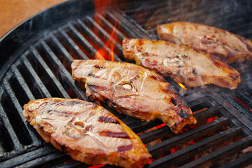 Raw lamb saddle back chop steak grilled as close-up on a charcoal grill with fire
